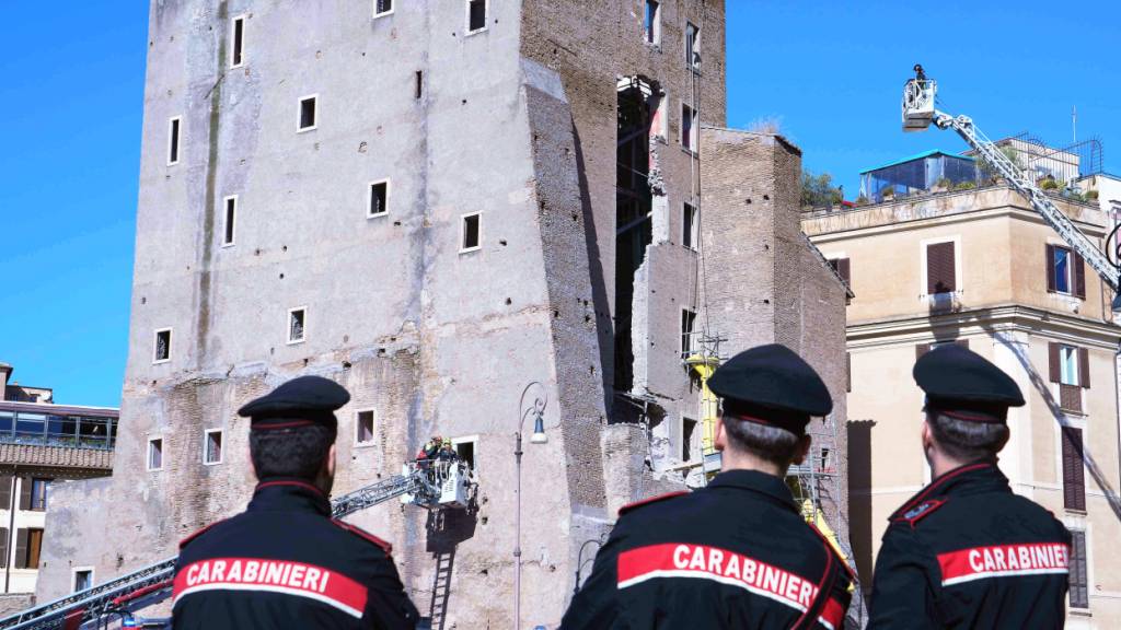 Polizeibeamte der Carabinieri beobachten nach dem Einsturz eines Gebäudeteils, an dem Restaurierungsarbeiten durchgeführt wurden, den Einsatz der Feuerwehrkräfte. Foto: Domenico Stinellis/AP/dpa