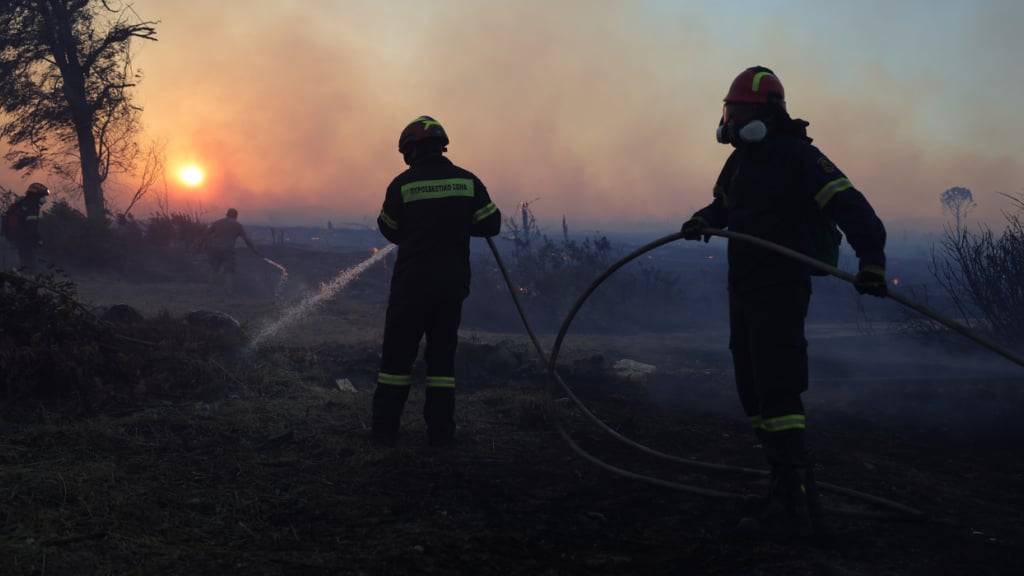 Feuerwehrleute versuchen, einen Flächenbrand im nordwestlichen Vorort Kryoneri zu löschen. Foto: Yorgos Karahalis/AP/dpa