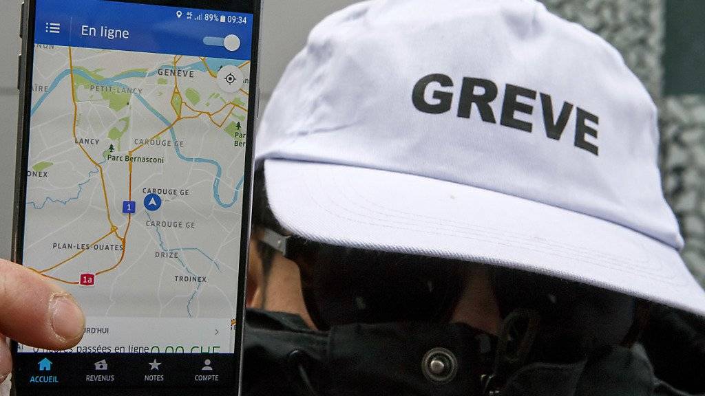 Ein streikender Chauffeur zeigt am Mittwoch vor dem Genfer Sitz von Uber in Carouge die Smartphone-Applikation des Fahrdienstes.