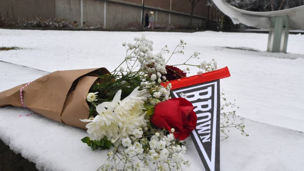 Ein Blumenstrauß liegt auf dem Schnee auf dem Campus der Brown University. Foto: Steven Senne/FR172182 AP/AP/dpa