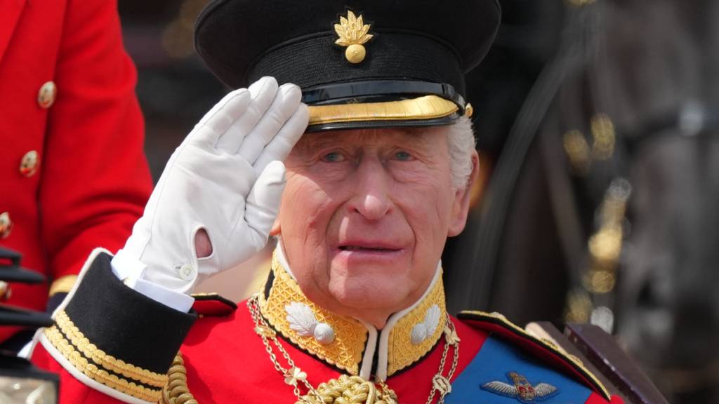 dpatopbilder - Der britische König Charles III. salutiert, während er gemeinsam mit Königin Camilla in einer offenen Kutsche bei der «Trooping the Colour», der jährlichen Geburtstagsparade des Königs, mitfährt. Foto: Kirsty Wigglesworth/AP/dpa