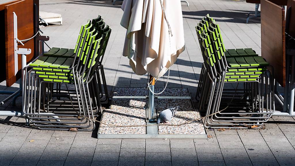Gestapelte Stühle und zusammengeklappte Tische stehen in der Außengastronomie eines geschlossenen Restaurants in der Hannoveraner Innenstadt. Foto: Julian Stratenschulte/dpa