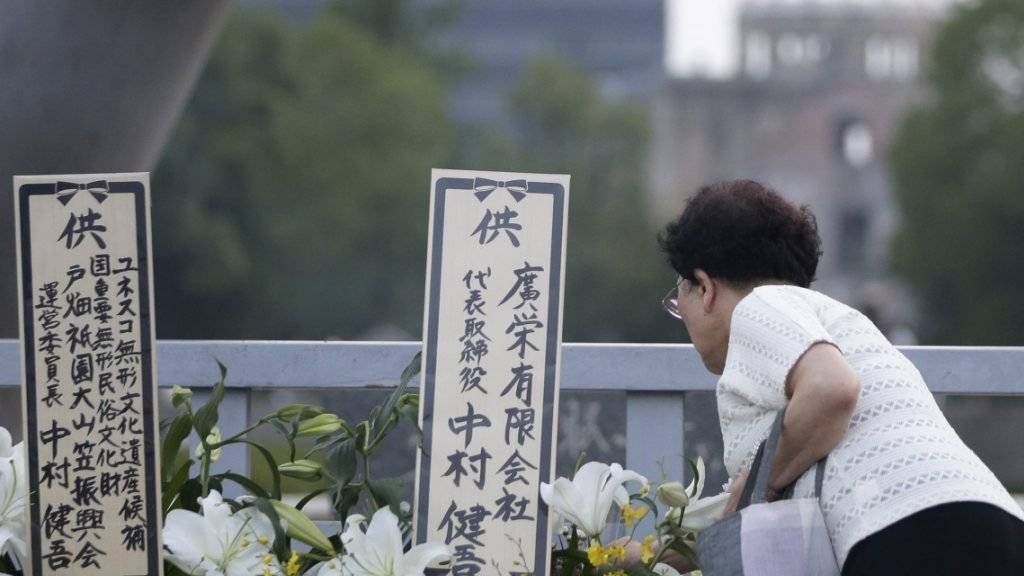 Eine Japanerin legt am 71. Jahrestag Blumen nieder für die Opfer des Atombombenangriffs von Hirsoshima. Im Hintergrund der Kenotaph, der an den Abwurf der amerikanischen Atombombe 1945 erinnert.