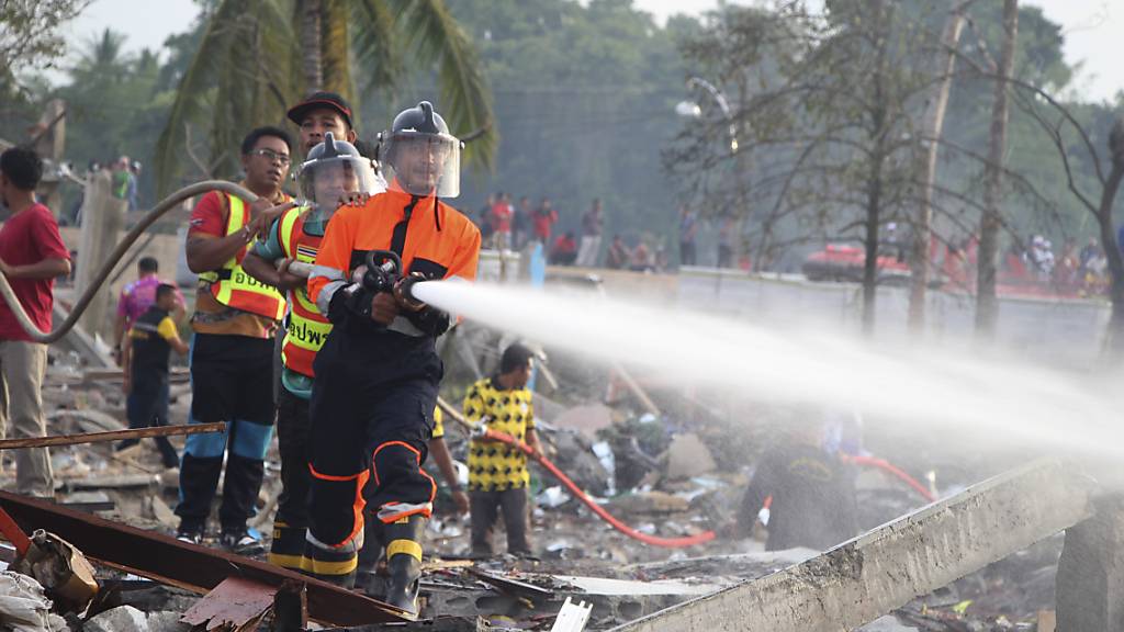 Einsatzkräfte der Feuerwehr löschen einen Brand in einem durch eine Explosion zerstörten Gebäude in Thailand. Foto: Kriya Tehtani/AP