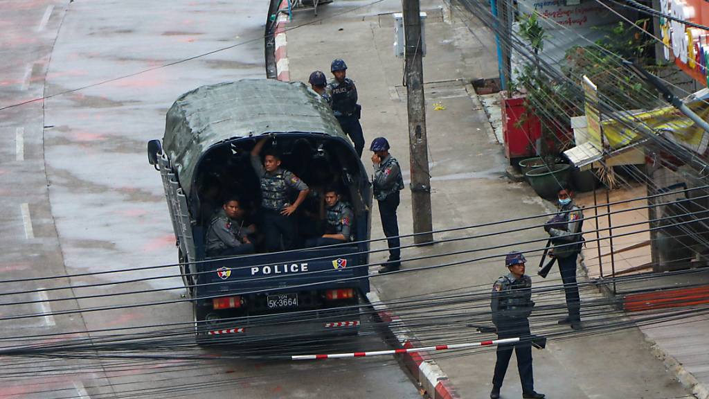 Sicherheitskräfte der Polizei warten in einem Polizeifahrzeug in Yangon. Foto: -/AP/dpa