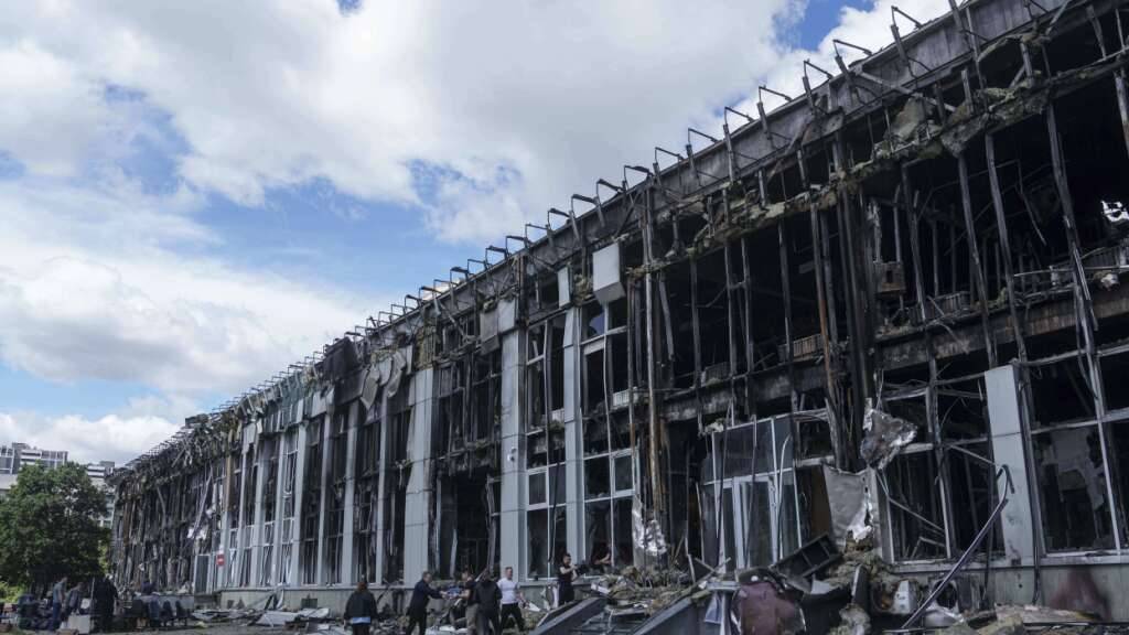 Menschen transportieren Habseligkeiten aus einem durch einen russischen Angriff zerstörten Bürogebäude in Kiew. Foto: Evgeniy Maloletka/AP/dpa
