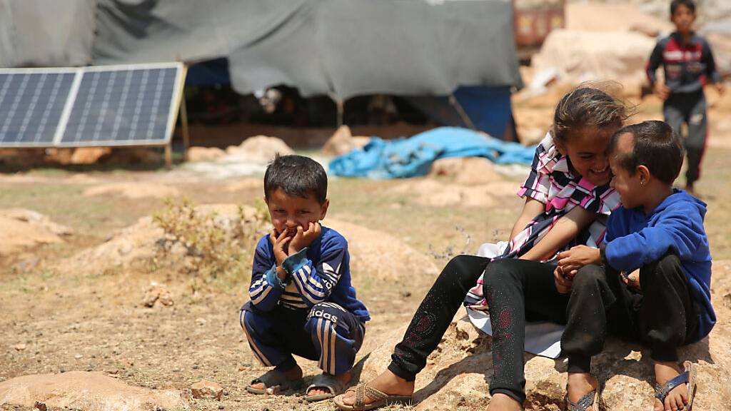 Geflüchtete Kinder sitzen in einem Flüchtlingslager nordwestlich von Aleppo auf einem Stein. (Archiv)