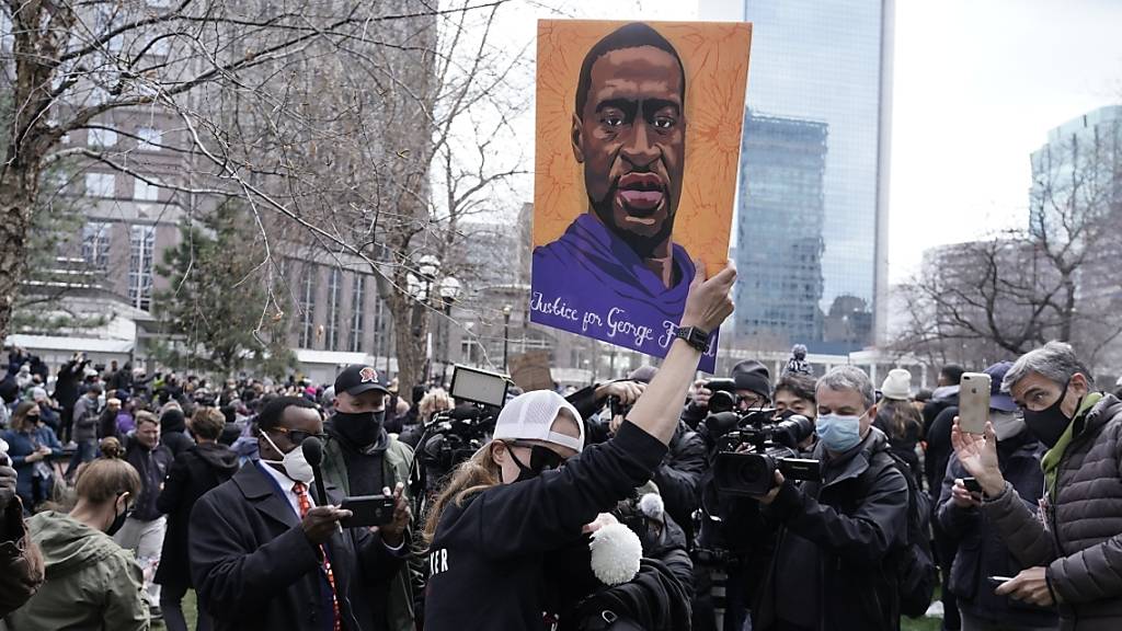 Menschen jubeln und halten ein Poster von George Floyd hoch nach der Urteilsverkündung im Mordprozess gegen den ehemaligen Polizeibeamte Derek Chauvin. Foto: Morry Gash/AP/dpa