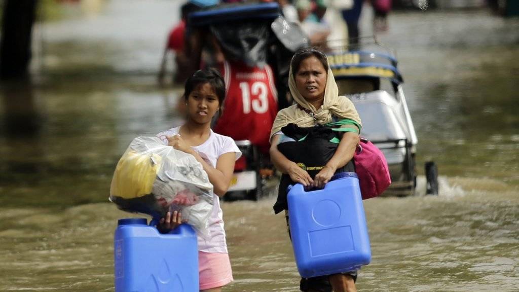 Die Bewohnerinnen von La Paz im Süden der Philippinen kommen nur mühsam auf den überfluteten Strassen voran.
