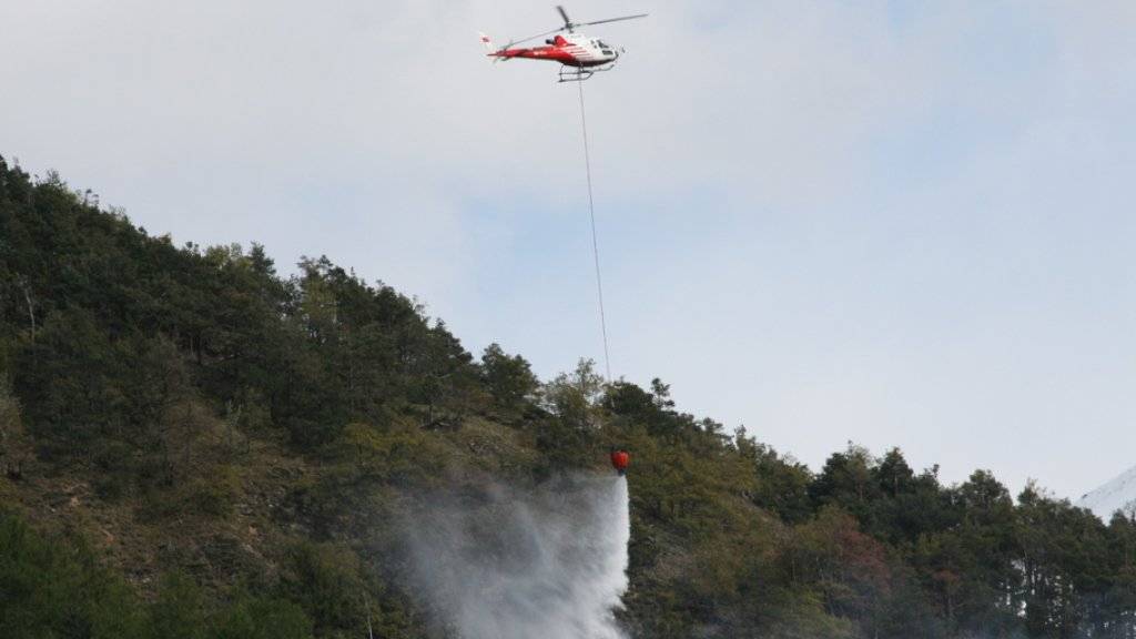 Ein Helikopter bekämpft am Mittwoch das Feuer in einem Waldstück bei Lens VS. (Archiv)