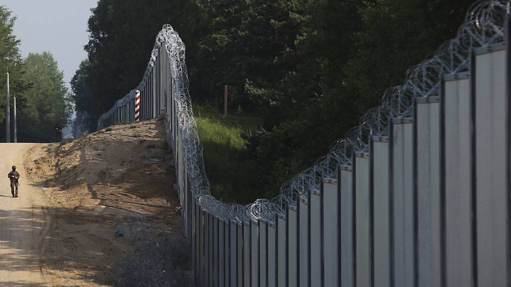 ARCHIV - Ein polnischer Grenzschutzbeamter patrouilliert im Bereich einer errichteten Metallmauer an der Grenze zwischen Polen und Belarus. Die Polen sollen gleichzeitig mit der Parlamentswahl in einem Referendum über einen bereits existierenden Zaun an der Grenze zu Belarus abstimmen. Foto: Michal Dyjuk/AP/dpa