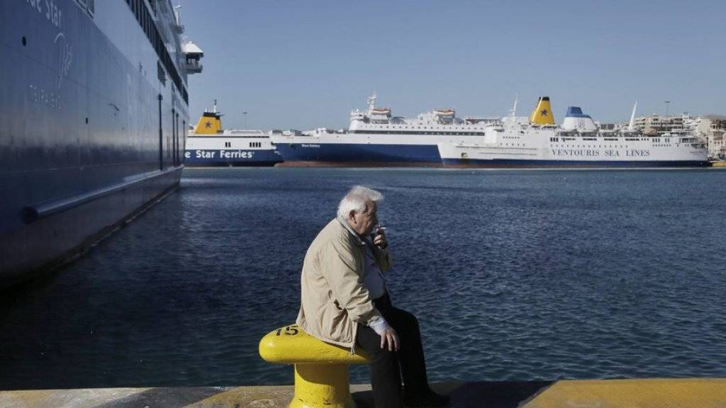 Ein Fährmann raucht vor stillstehenden Fähren im Hafen von Piräus. Die griechischen Seeleute protestieren mit dem Streik gegen die Kürzung ihrer Renten