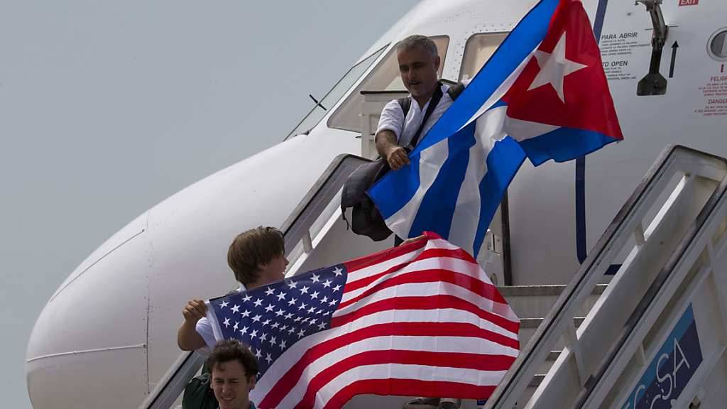 Zwei Passagiere entsteigen in Santa Clara der Maschine mit den Nationalflaggen beider Länder