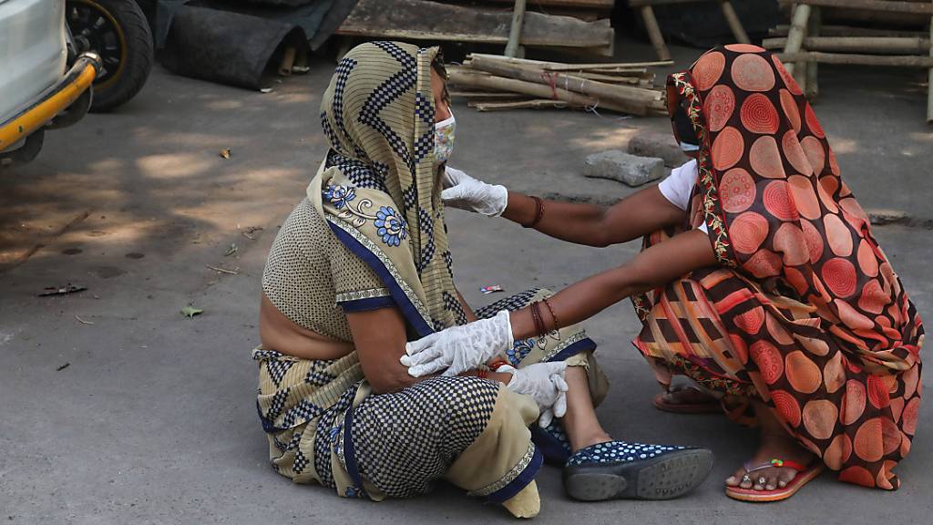 Die Angehörige eines Covid-19-Opfers wird während der Einäscherung des Leichnams im Krematorium Nigambodh Ghat in Neu-Delhi getröstet.
