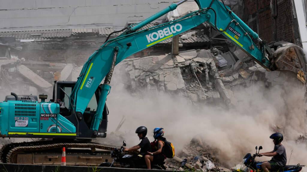 Zwei Tage nach dem Erdbeben fahren Menschen an einem Bagger vorbei, der Trümmer beseitigt. Foto: Fernando Vergara/AP/dpa