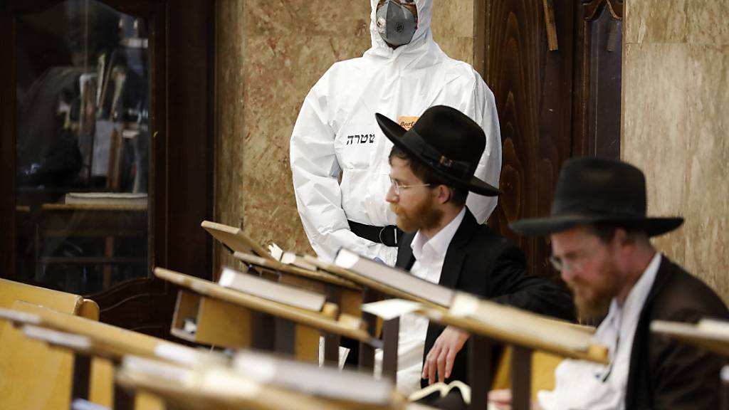 Ein israelischer Polizeibeamter betrachtet zwei orthodoxe Juden in einer Synagoge in Tel Aviv. (Archivbild)