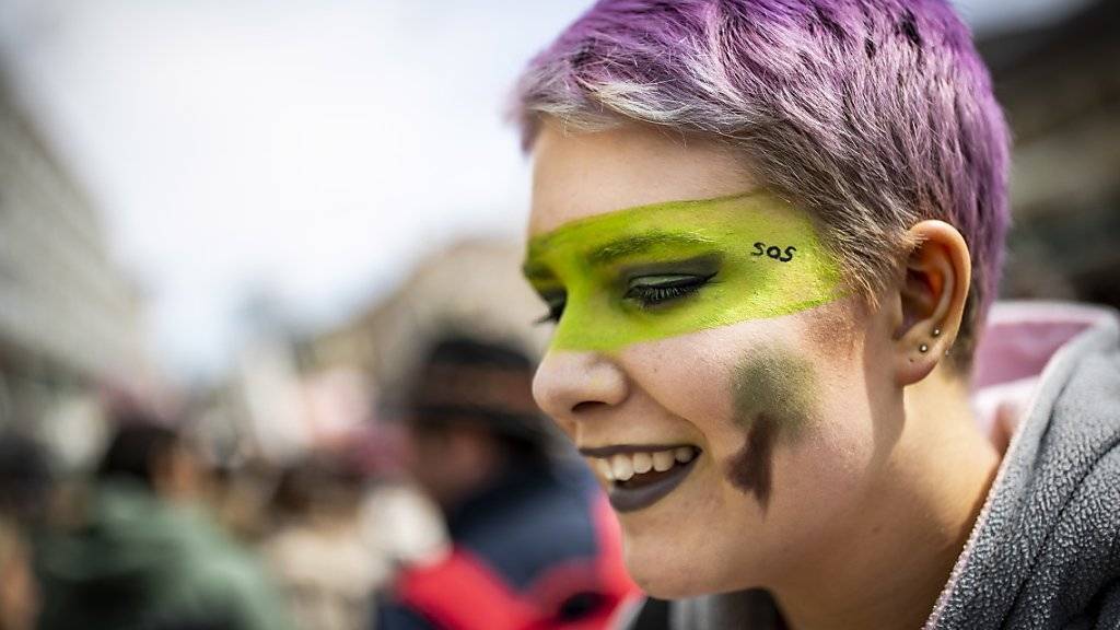 Farbe und ein Lächeln müssen auch sein: Junge Frau an der Klimademo in Lausanne.