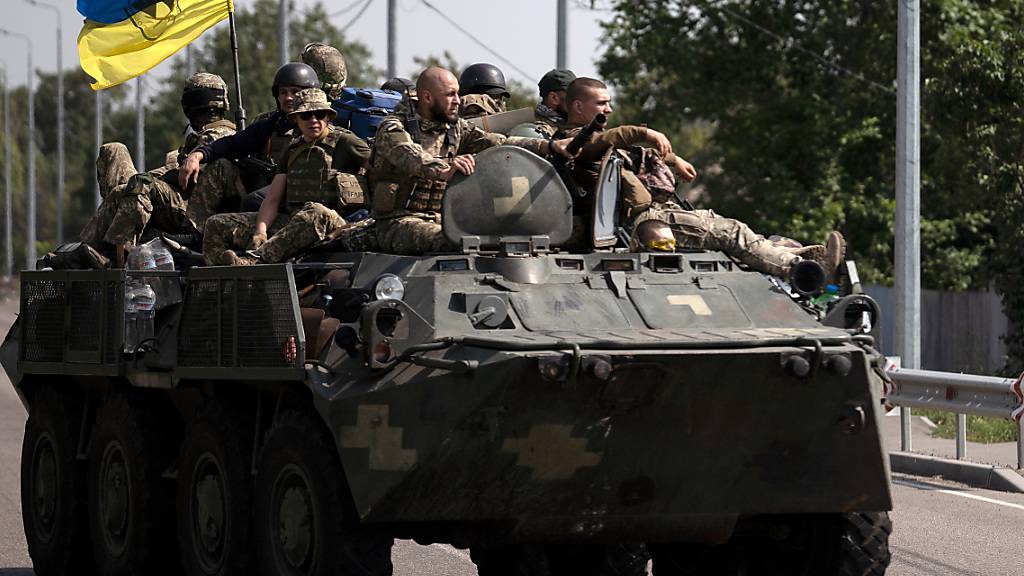 Ukrainische Soldaten fahren auf einem gepanzerten Fahrzeug auf einer Straße.