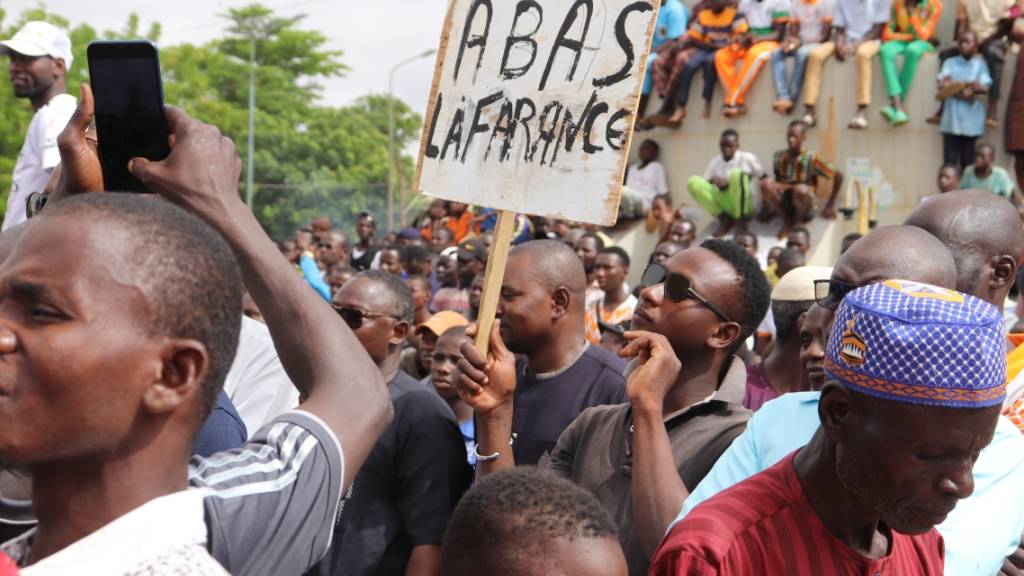 dpatopbilder - Menschen demonstrieren am 03.08.2023 in Nigers Hauptstadt Niamey, um damit ihre Unterstützung für die Putschisten zu zeigen. Ein junger Mann hält dabei ein Schild mit der Aufschrift «A bas la France» (Nieder mit Frankreich) in die Höhe. Foto: 1