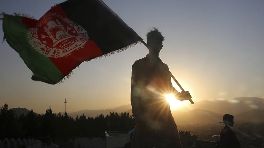dpatopbilder - ARCHIV - Ein Mann schwenkt eine afghanische Nationalflagge. Foto: Rafiq Maqbool/AP/dpa