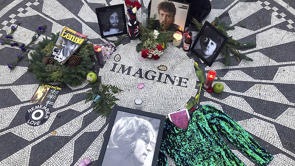 ARCHIV - Fotos, Blumen und Kerzen stehen auf der Gedenkstätte Strawberry Fields im Central Park zur Erinnerung an John Lennon. Vor 50 Jahren veröffentlichte John Lennon seinen Song «Imagine». Das Lied gilt bis heute als hoffnungsvolle Hymne für den Weltfrieden, obwohl einige Zeilen immer wieder zu Diskussionen anregen. (zu dpa «Ewige Friedenhymne des Träumers: John Lennons «Imagine» wird 50») Foto: Mark Lennihan/AP/dpa