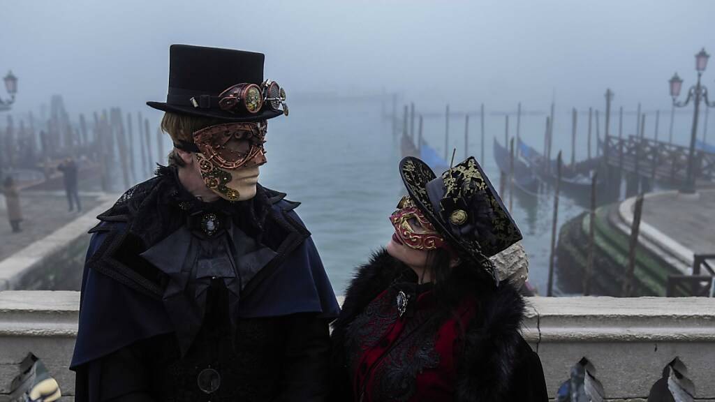 Ein Pärchen ist kostümiert und trägt Masken. Der diesjährige Karneval in Venedig hat das Motto «To the East. Die erstaunliche Reise des Marco Polo» und ist eine Hommage an den berühmten Kaufmann und Reisenden Marco Polo anlässlich seines 700. Todestags. Foto: Luca Bruno/AP/dpa