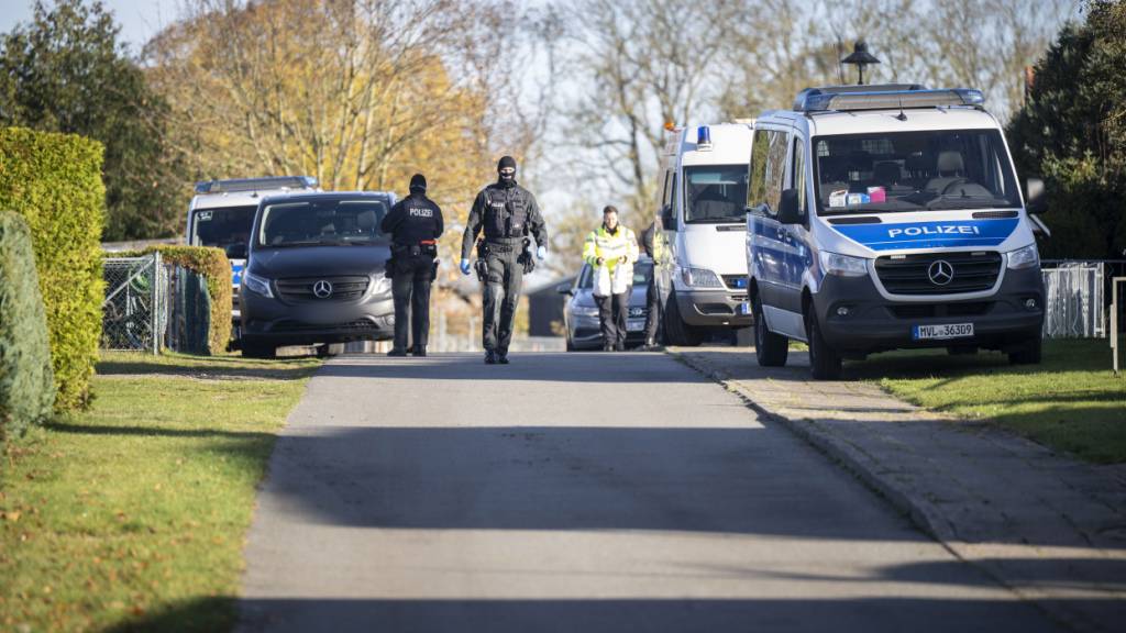 Polizeiautos stehen vor einem Wohnhaus in Reimershagen. Nach zahlreichen Hinweisen bei «Aktenzeichen XY» durchsucht die Polizei erneut mehrere Objekte in Reimershagen und im Nachbarort Rum Kogel. Foto: Philip Dulian/dpa - ACHTUNG: Kennezeich(en) wurde(n) aus rechtlichen Gründen gepixelt