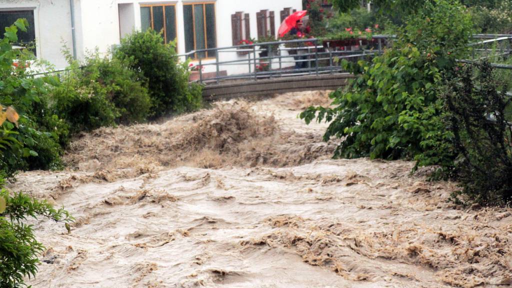 Ein Passant steht auf einer Brücke über den Auerbach im Ortsteil Au im Landkreis Rosenheim. Foto: Josef Reisner/dpa