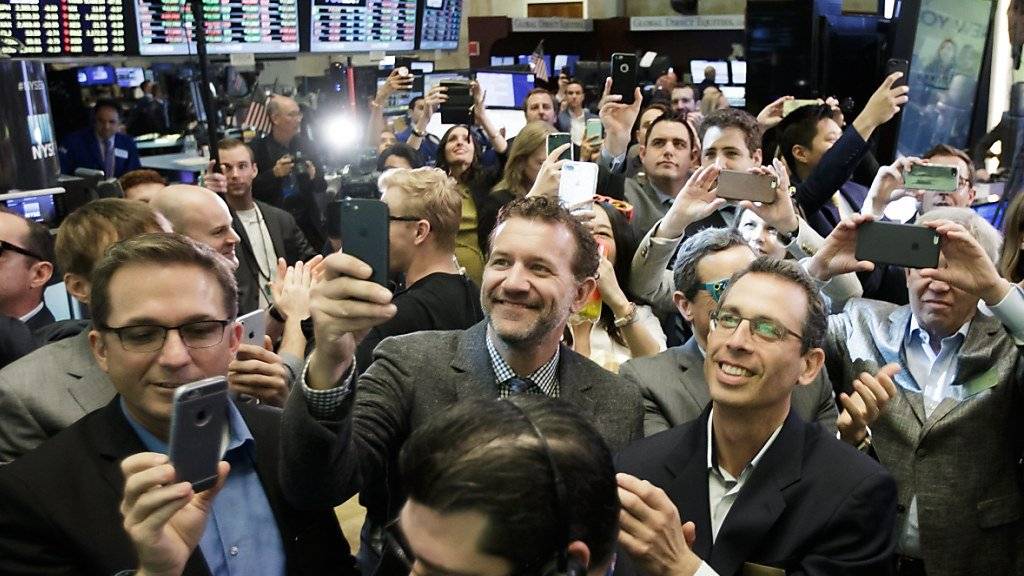 Händler an der New Yorker Börse halten den Börsenstart von Snap Inc. auf ihren Smartphones fest