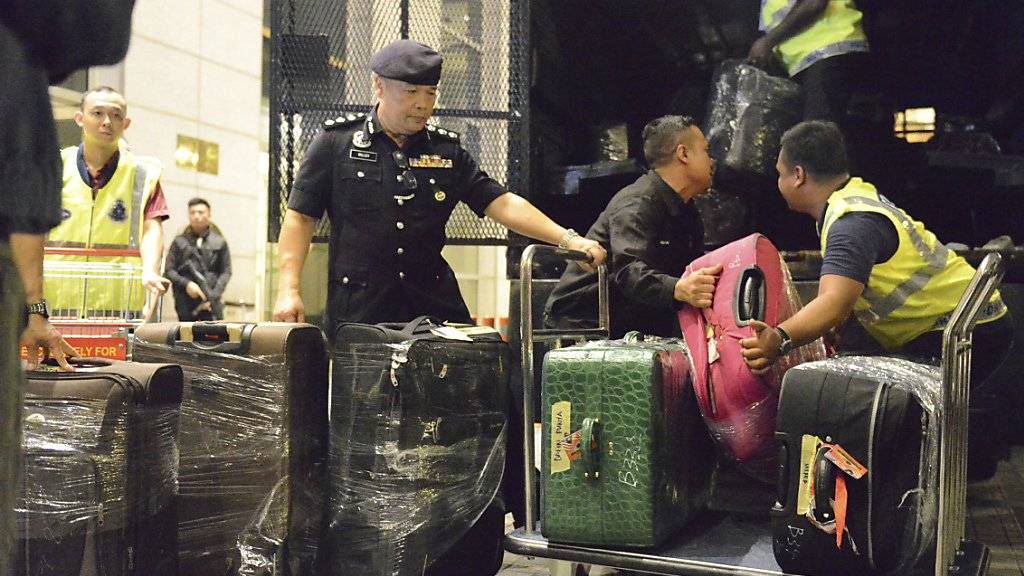 Polizisten verladen dutzende Kisten und Koffer voller Luxusartikel, die bei einer Razzia bei Malaysias Ex-Regierungschef Najib gefunden wurden.