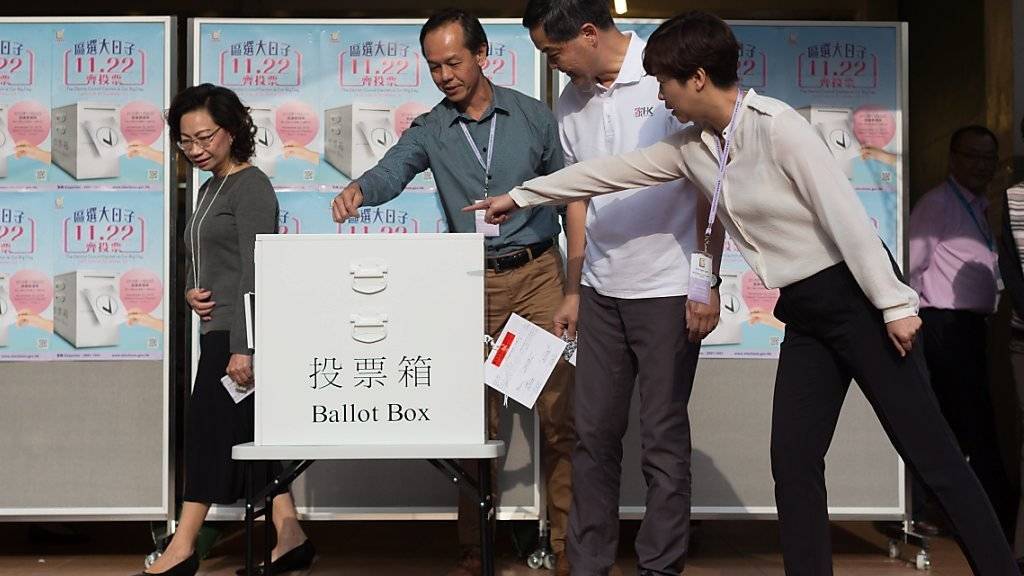 Demokratie will gelernt sein: Mitarbeiter von Hongkongs Regierungschef Leung Chun-ying (weisses Hemd) zeigen ihm, wo man den Stimmzettel in die Urne stecken kann.