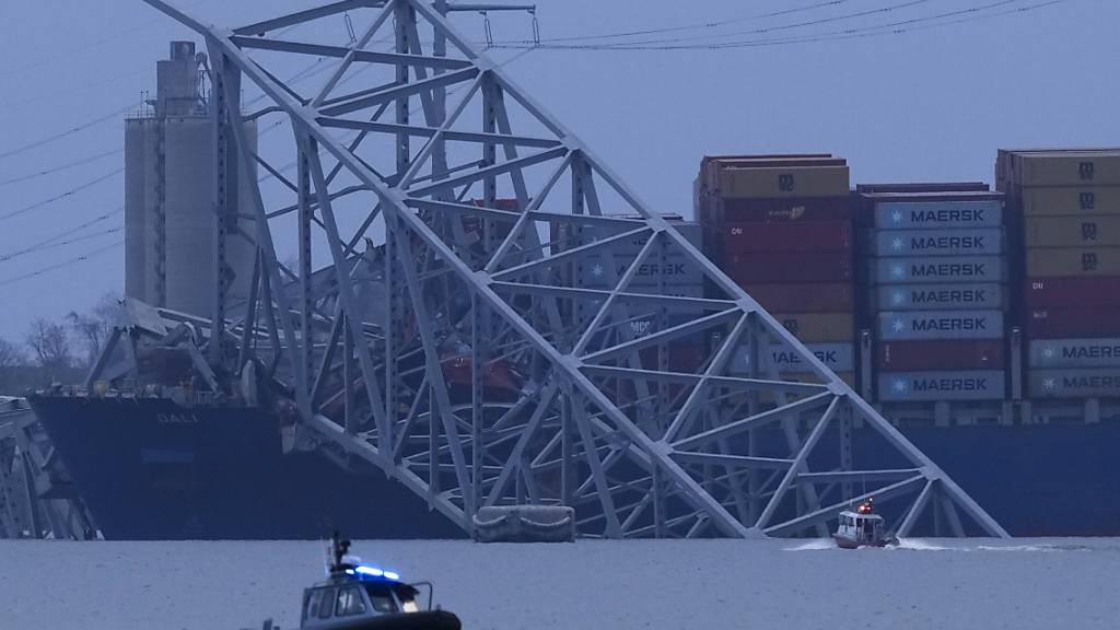 Ein Containerschiff liegt bei Einbruch der Dunkelheit am Wrack der Francis Scott Key Bridge. Foto: Matt Rourke/AP
