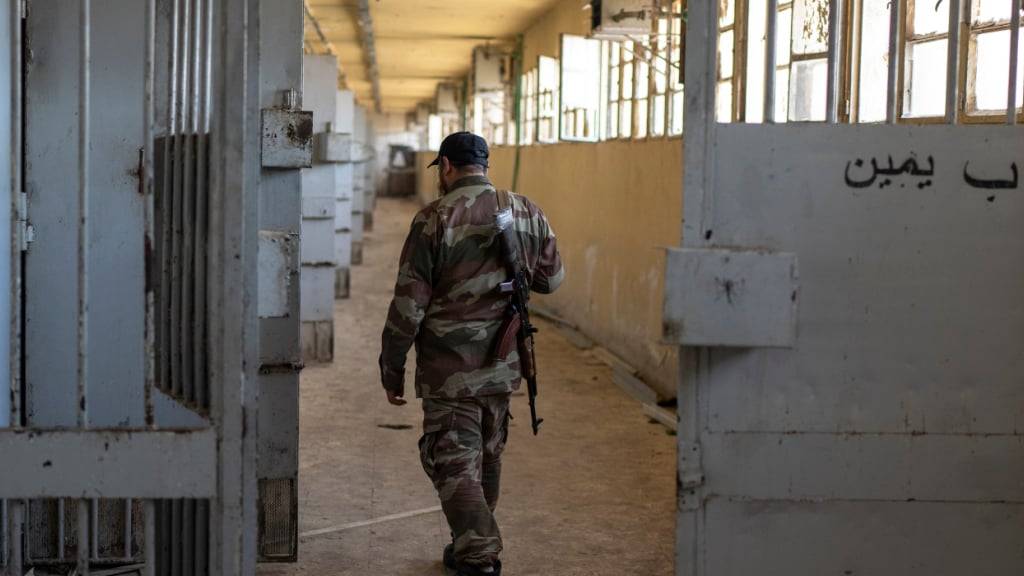 ARCHIV - Ein Mitglied der neuen syrischen Sicherheitskräfte geht die Zellengalerie des Militärgefängnisses Saidnaja am Stadtrand von Damaskus entlang. (zu dpa: «Assads Syrien: Acht Millionen Menschen unter Beobachtung») Foto: Mosa'ab Elshamy/AP/dpa