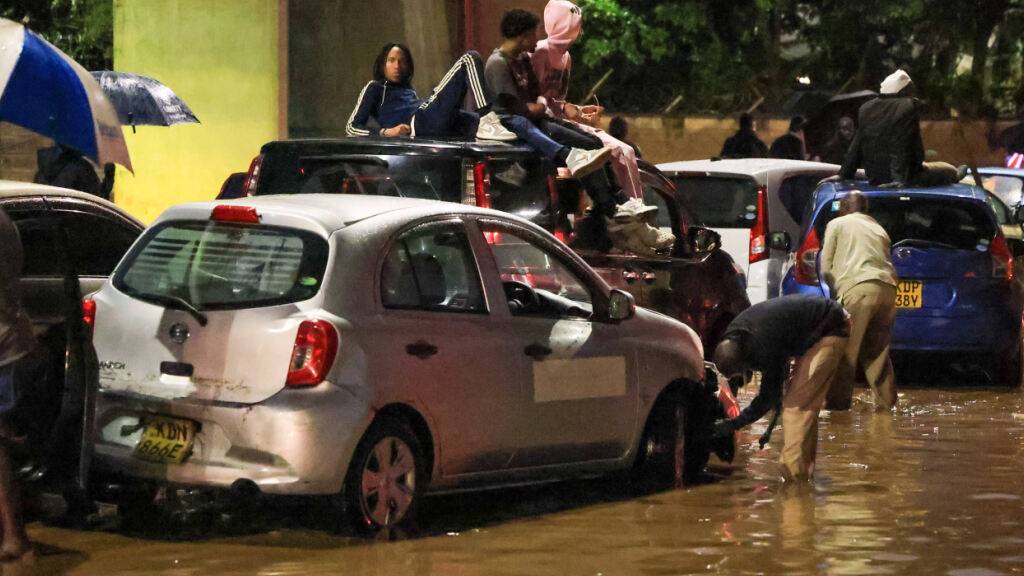 dpatopbilder - Menschen klettern auf ihre Autos, nachdem schwere Regenfälle die Straßen in Nairobi überflutet haben. Foto: Andrew Kasuku/AP/dpa