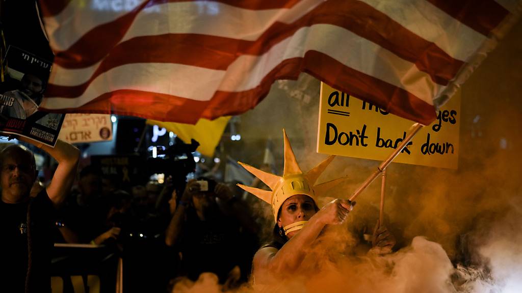 Ein Demonstrant schwenkt die US-Fahne während eines Protestes gegen die Regierung von Ministerpräsident Netanjahu und fordert die Freilassung von Geiseln, die im Gazastreifen von der islamistische Hamas festgehalten werden. Foto: Leo Correa/AP/dpa