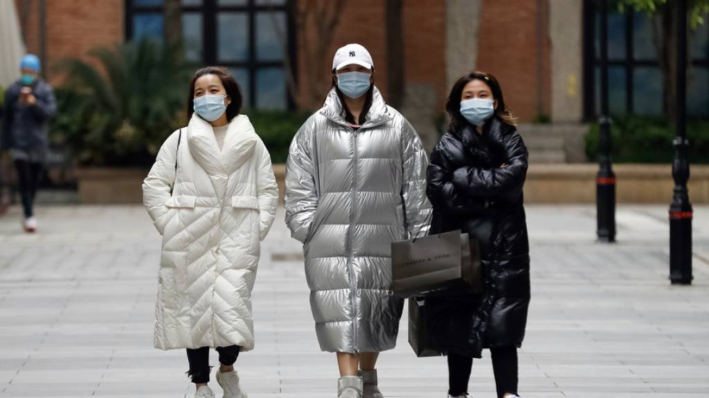 Passanten am Montag in Wuhan, wo die Pandemie ihren Ausgang nahm. Auch Experten fragen sich, warum die Corona-Zahlen aus China eher niedrig sind.