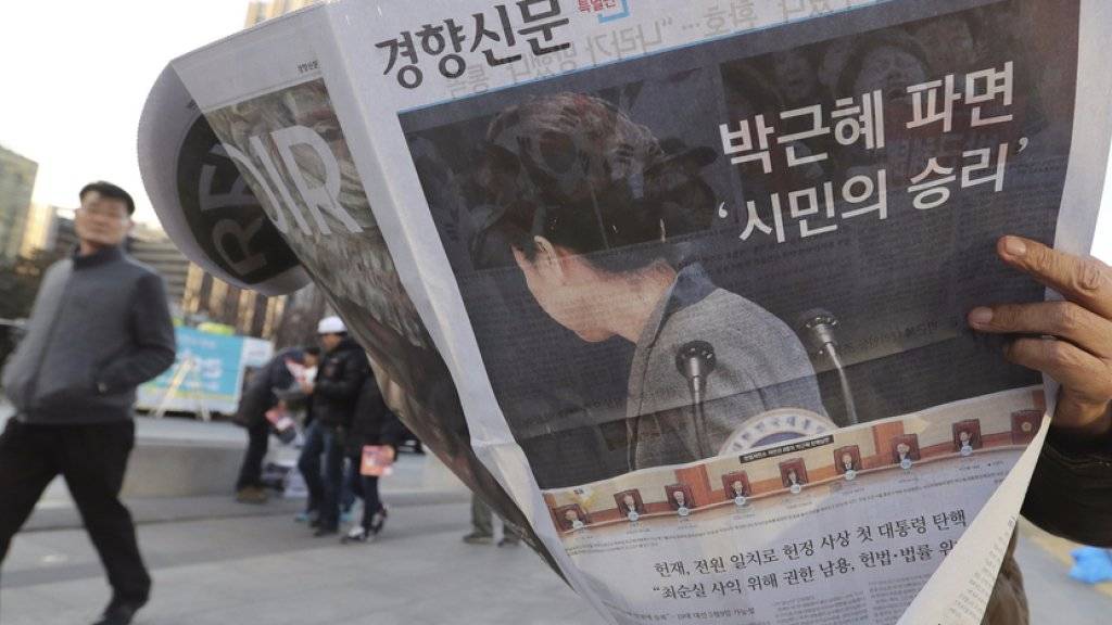 Mann am Freitag in Seoul mit Zeitung, die das Ende von Parks Präsidentschaft in Südkorea verkündet.