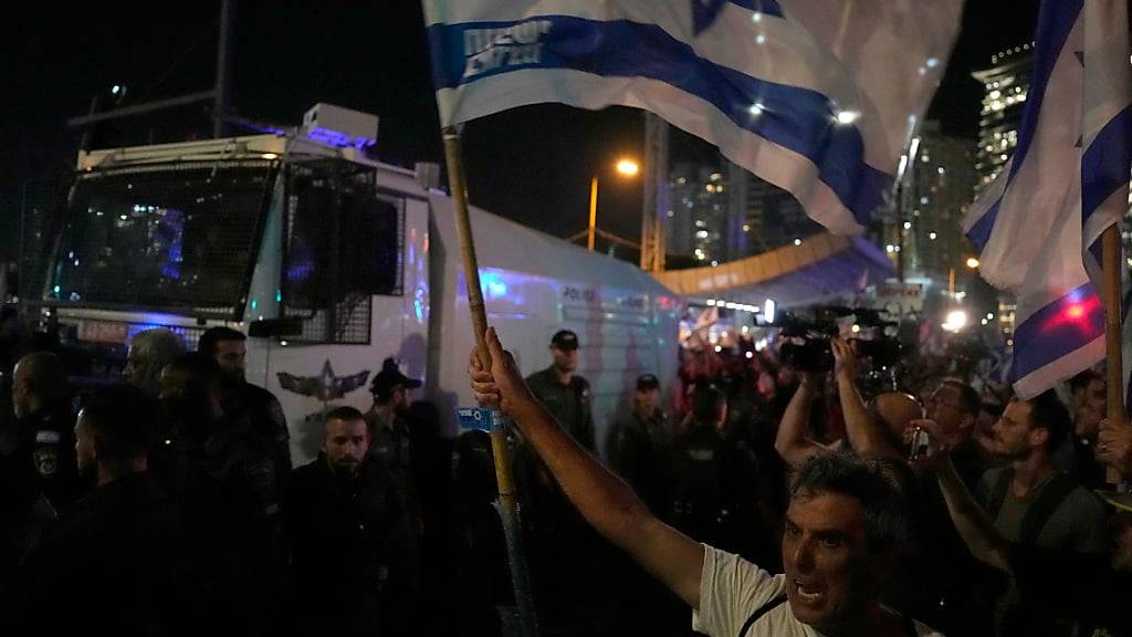 Demonstranten halten israelische Fahnen hoch, während sie an einer Demonstration gegen die Justizreform teilnehmen. Israels Parlament hat ein Kernelement zum Umbau der Justiz im Land verabschiedet. Foto: Ariel Schalit/AP/dpa