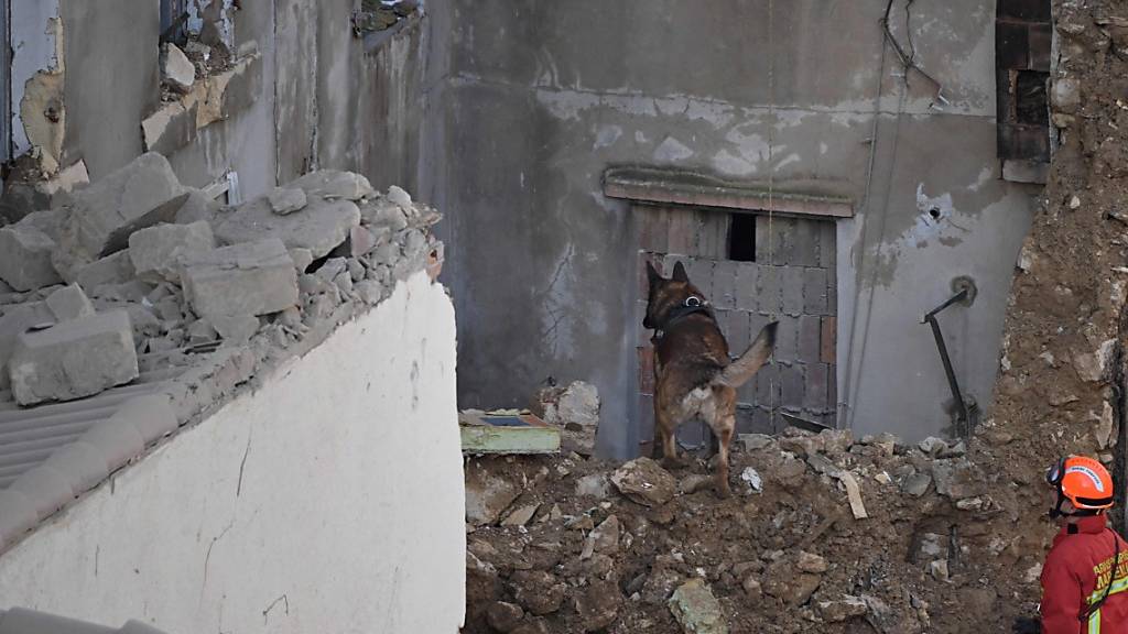 Ein Feuerwehrmann und sein Spürhund suchen nach Opfern in den Trümmern, einen Tag nachdem ein Gebäude in der Innenstadt eingestürzt ist. Rettungskräfte haben nach dem Einsturz eines Gebäudes in der Innenstadt von Marseille eine fünfte Leiche in den Trümmern entdeckt. Foto: Nicolas Tucat/AFP/dpa