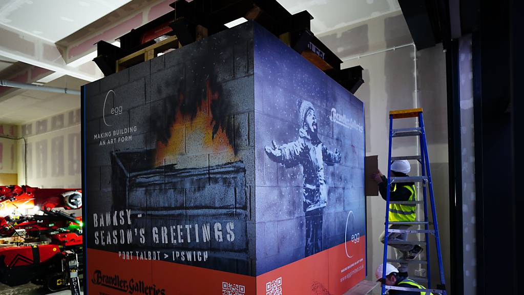 Arbeiter sichern eine Kiste mit dem Werk «Season's Greetings» («Frohe Festtage») des Straßenkünstlers Banksy.