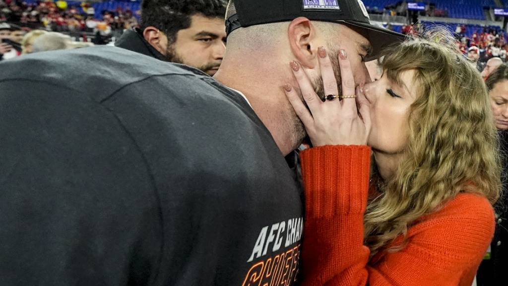 ARCHIV - Die Musikerin Taylor Swift (r) küsst Kansas City Chiefs Tight End Travis Kelce nach einem NFL-Footballspiel auf dem Spielfeld. Foto: Julio Cortez/AP/dpa