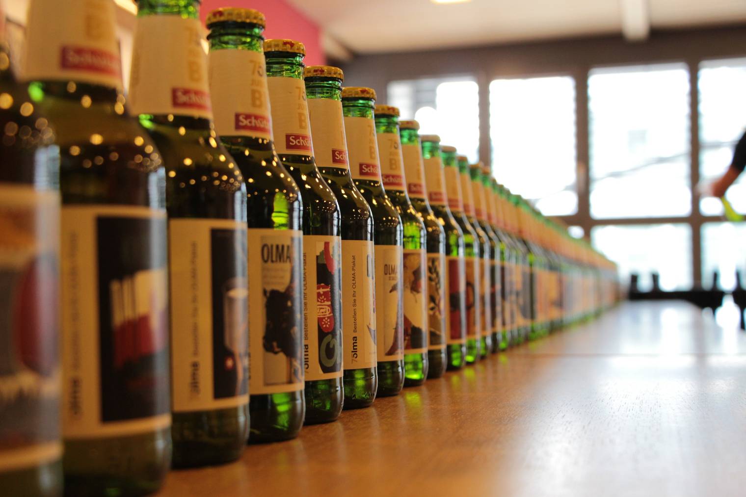 75 Bierflaschen aneinandergereiht, jede hat den gleichen Inhalt, jede hat eine andere Etikette. (Bild: FM1Today/Fabienne Engbers)