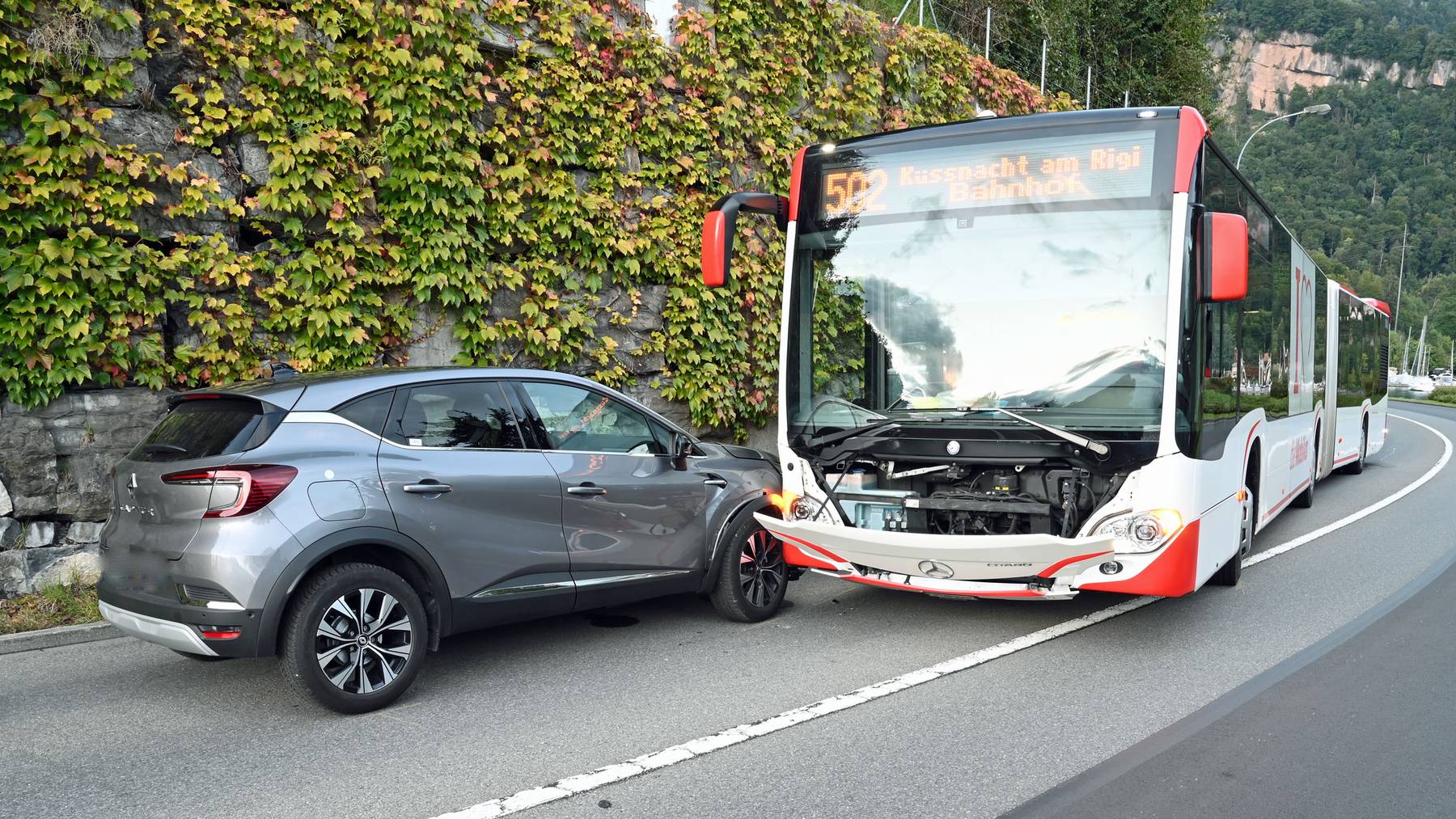 Unfall zwischen grauem Auto und rot-weissem Bus.