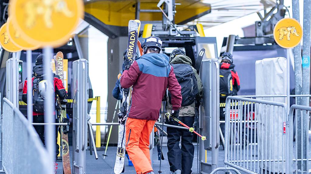 Menschen gehen mit ihren Skiern zu einer Gondel in der Talstation des Skigebiets Zillertal Arena. Foto: Expa/Johann Groder/APA/dpa