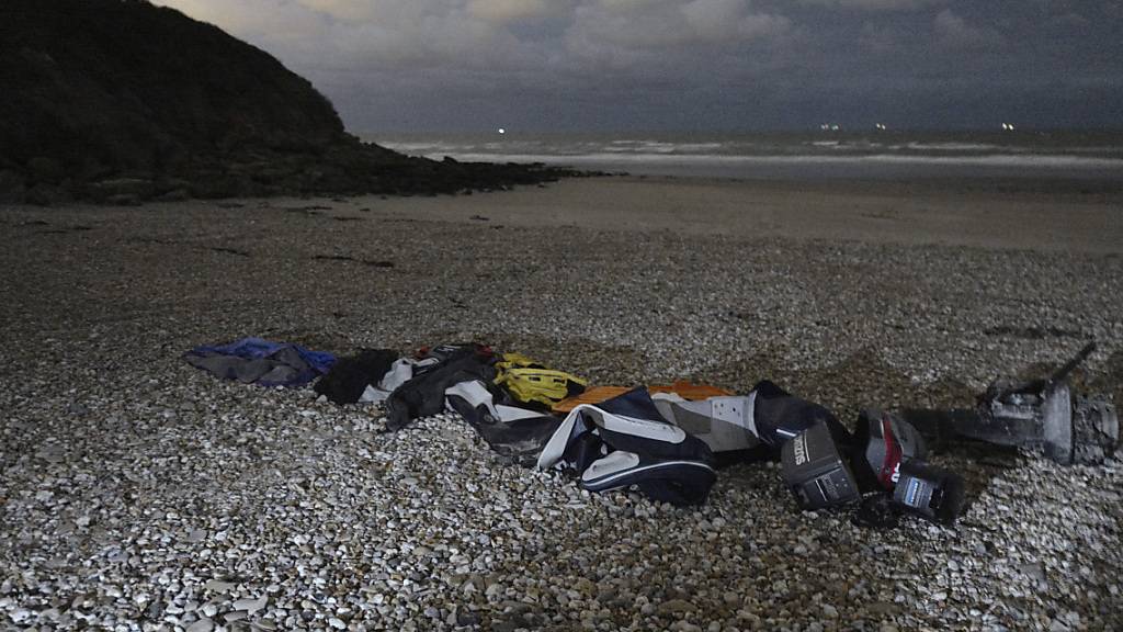 Schwimmwesten, Schlafsäcke und ein beschädigtes aufblasbares Schlauchboot liegen am Ufer in Calais. Bei einem Krisentreffen zur Migration über den Ärmelkanal haben Frankreich, Belgien, die Niederlande und Deutschland einen härteren Kampf gegen Schleuser vereinbart. Foto: Rafael Yaghobzadeh/AP/dpa