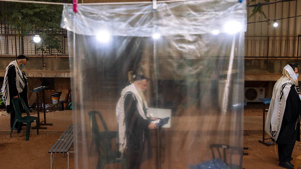 dpatopbilder - Ultraorthodoxe Juden halten den nötigen Mindestabstand ein und tragen Mundschutz, während eines Morgengebets vor ihren Häusern, da in den Synagogen nur maximal zwanzig Personen gleichzeitig beim Gebet zugelassen sind. Foto: Oded Balilty/AP/dpa