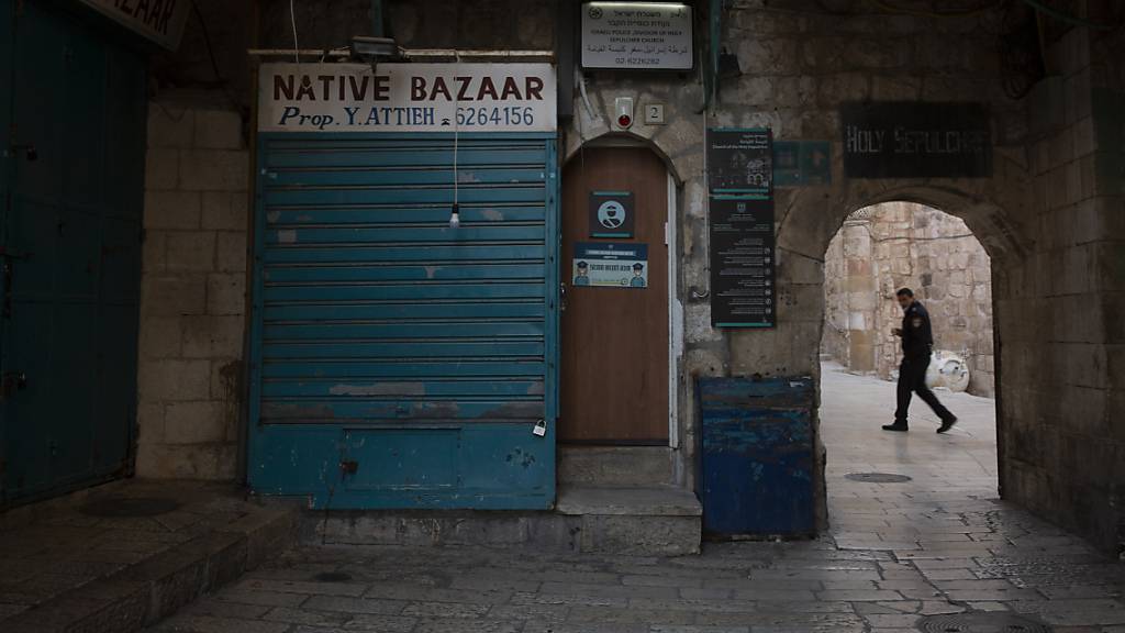 ARCHIV - Ein israelischer Polizist geht in der Altstadt von Jerusalem, unweit des Eingangs der Grabeskirche, an geschlossene Souvenirläden vorbei. Foto: Maya Alleruzzo/AP/dpa
