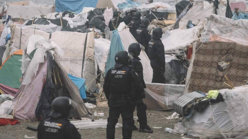 dpatopbilder - Bereitschaftspolizisten stehen während der Räumung zwischen den Unterkünften des provisorischen Migrantenlagers am Strand «El Trampolin» in Ceuta. Foto: Fabian Suspensivo/ZUMA Press Wire/dpa