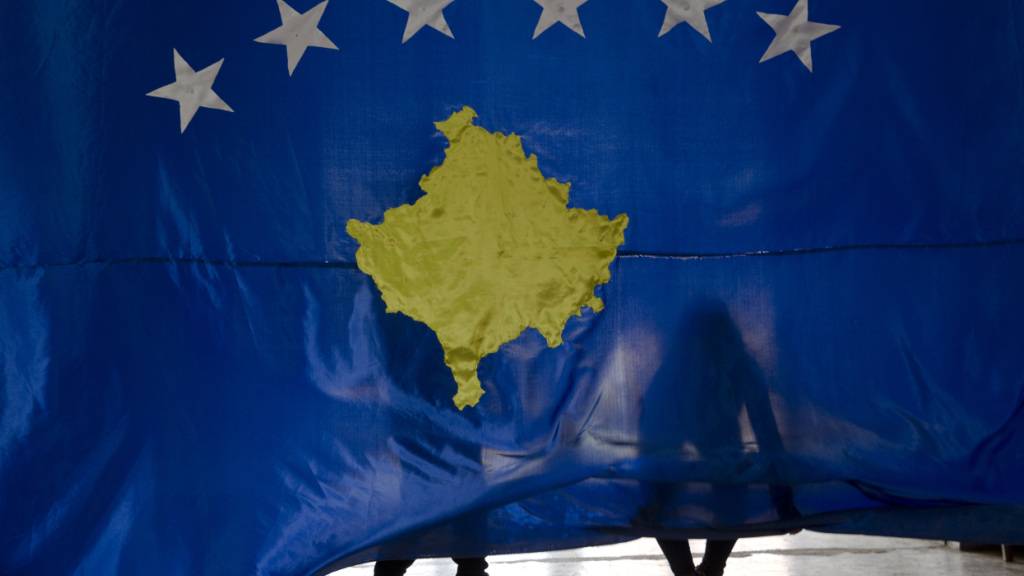 ARCHIV - 16.02.2018, Kosovo, Pristina: Zwei Schüler der Hasan Zyko Kamberi Schule halten bei einer Zeremonie zum zehnten Jahrestag der Unabhängigkeit des Kosovo eine Nationalflagge des Landes. Foto: Visar Kryeziu/AP/dpa