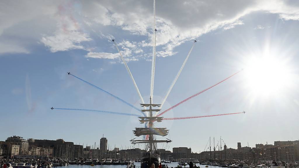 Das olympische Feuer kommt, begleitet von einer Flug-Show, per Schiff im Hafen von Marseille an